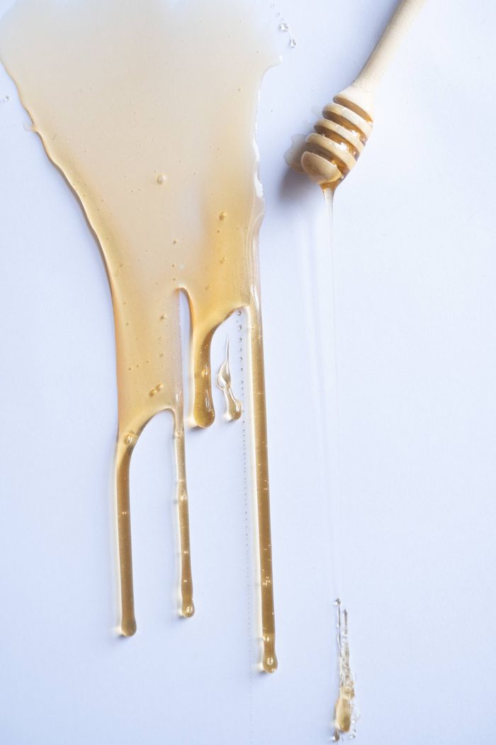services-bg Honey flowing from a honey dipper onto a clean surface, showcasing food photography.